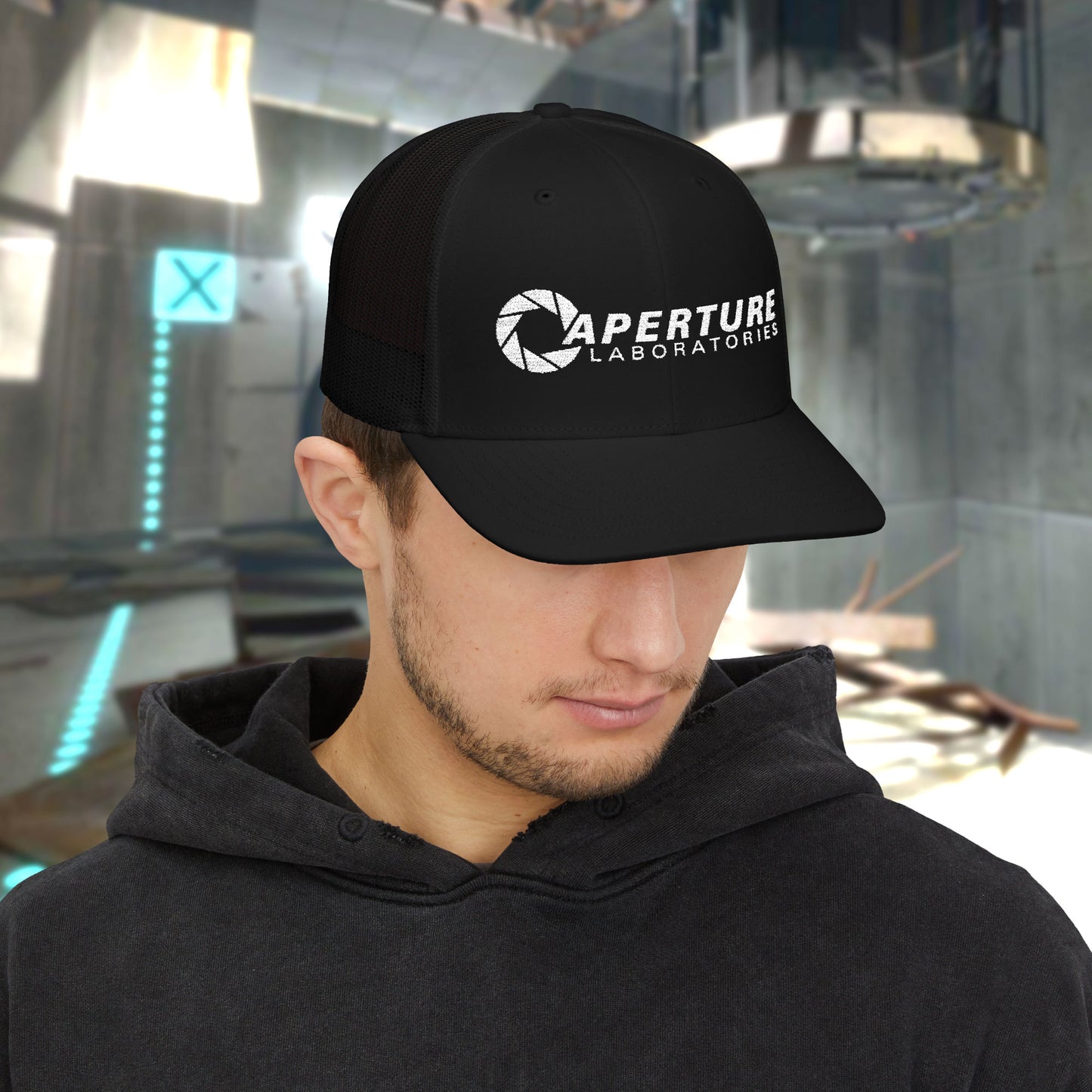 Male model wearing a black colored Richardson 112 Snapback Trucker Cap featuring the embroidered logo of the fictional company Aperture Laboratories from the video game Portal and Portal 2, sold by ScriptedBrand. 