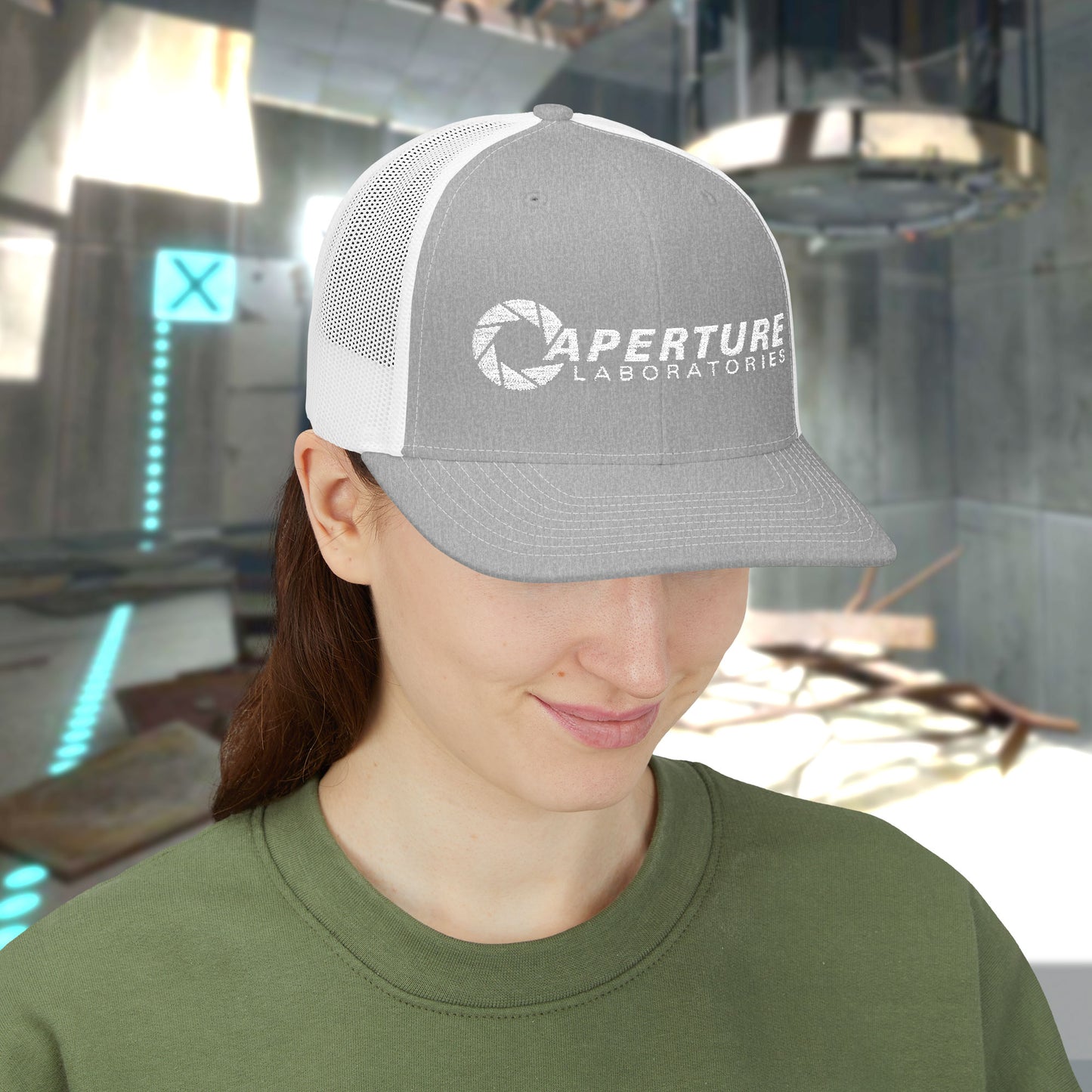 Female model wearing a heather grey/white colored Richardson 112 Snapback Trucker Cap featuring the embroidered logo of the fictional company Aperture Laboratories from the video game Portal and Portal 2, sold by ScriptedBrand. 