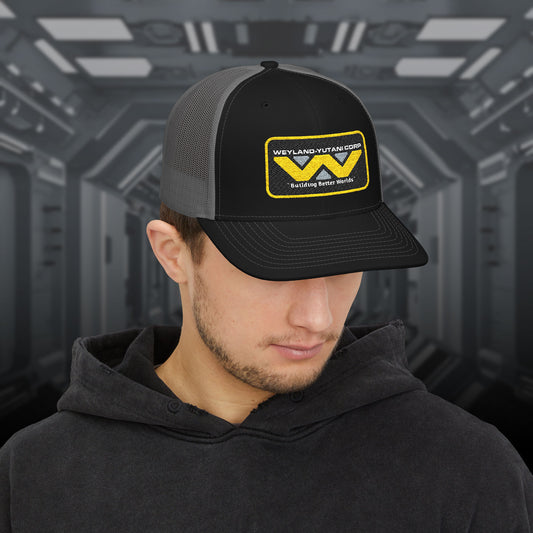 Man wearing black-charcoal Embroidered Snapback Trucker Cap with logo of Weyland-Yutani from the Alien movie franchise.