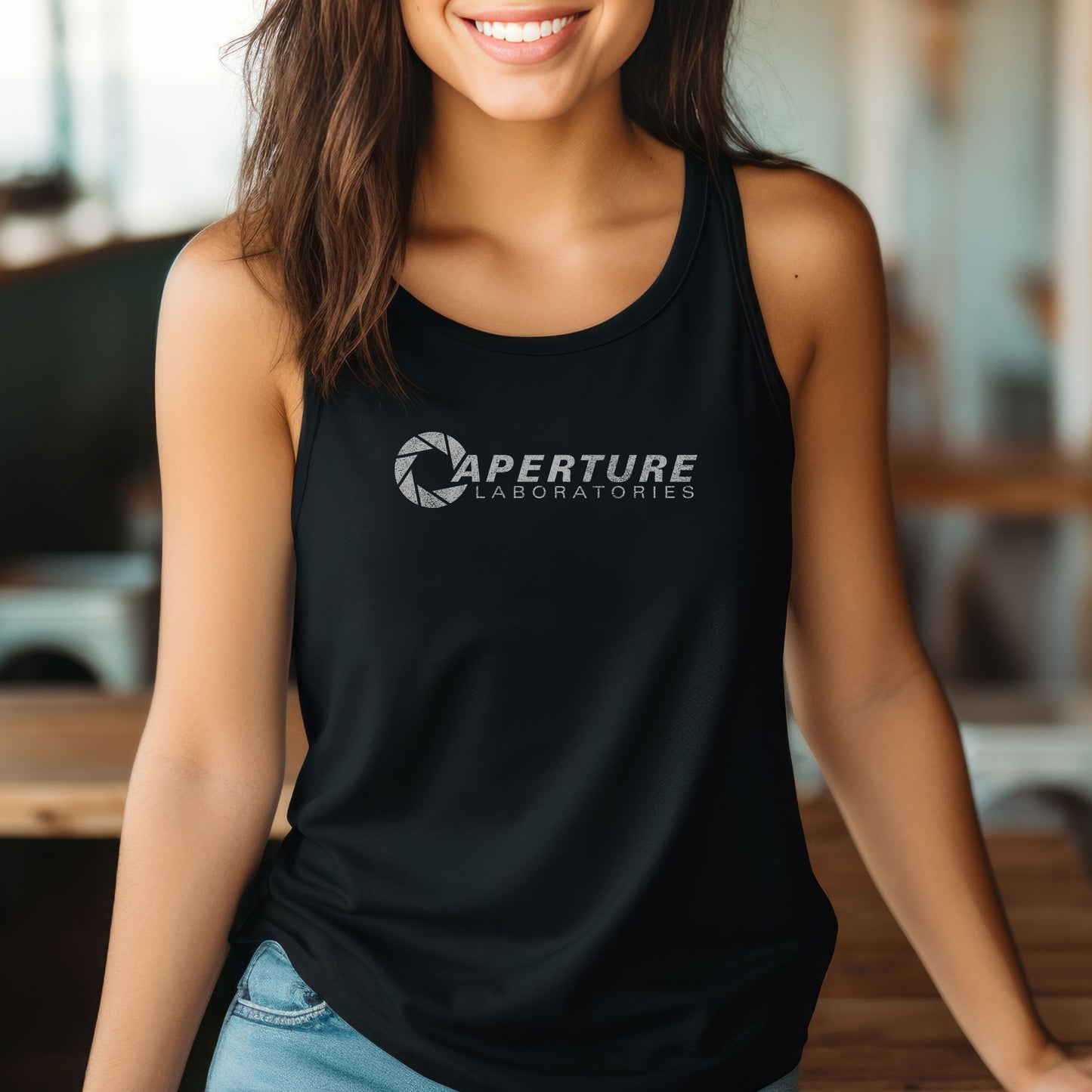 Female model wearing a black colored Women's Racerback Tank Top Shirt featuring the Aperture Laboratories logo from the video games Portal and Portal 2 in a vintage distressed style, sold by ScriptedBrand. 