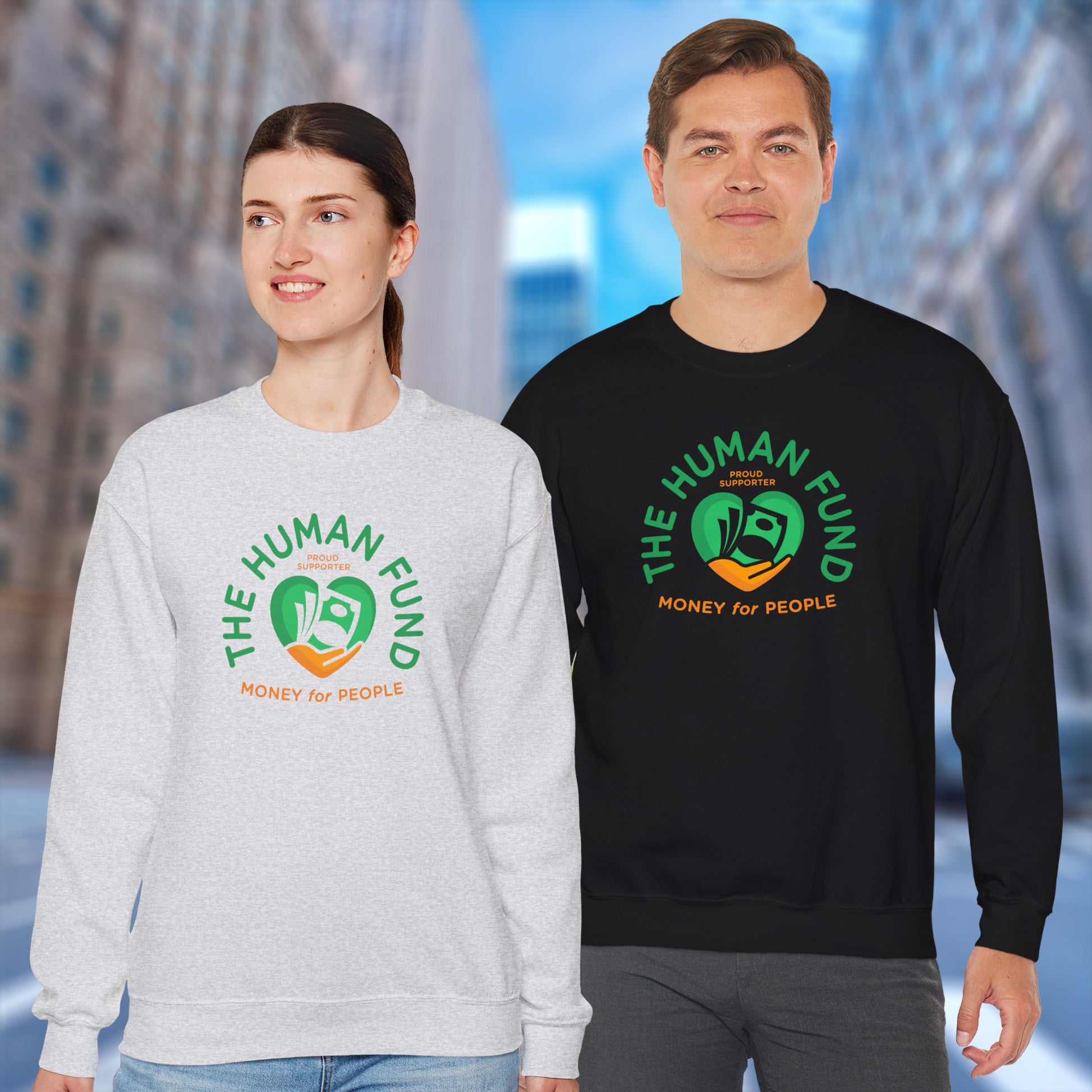 Two people wearing 'The Human Fund' sweatshirts with a blurred cityscape background.