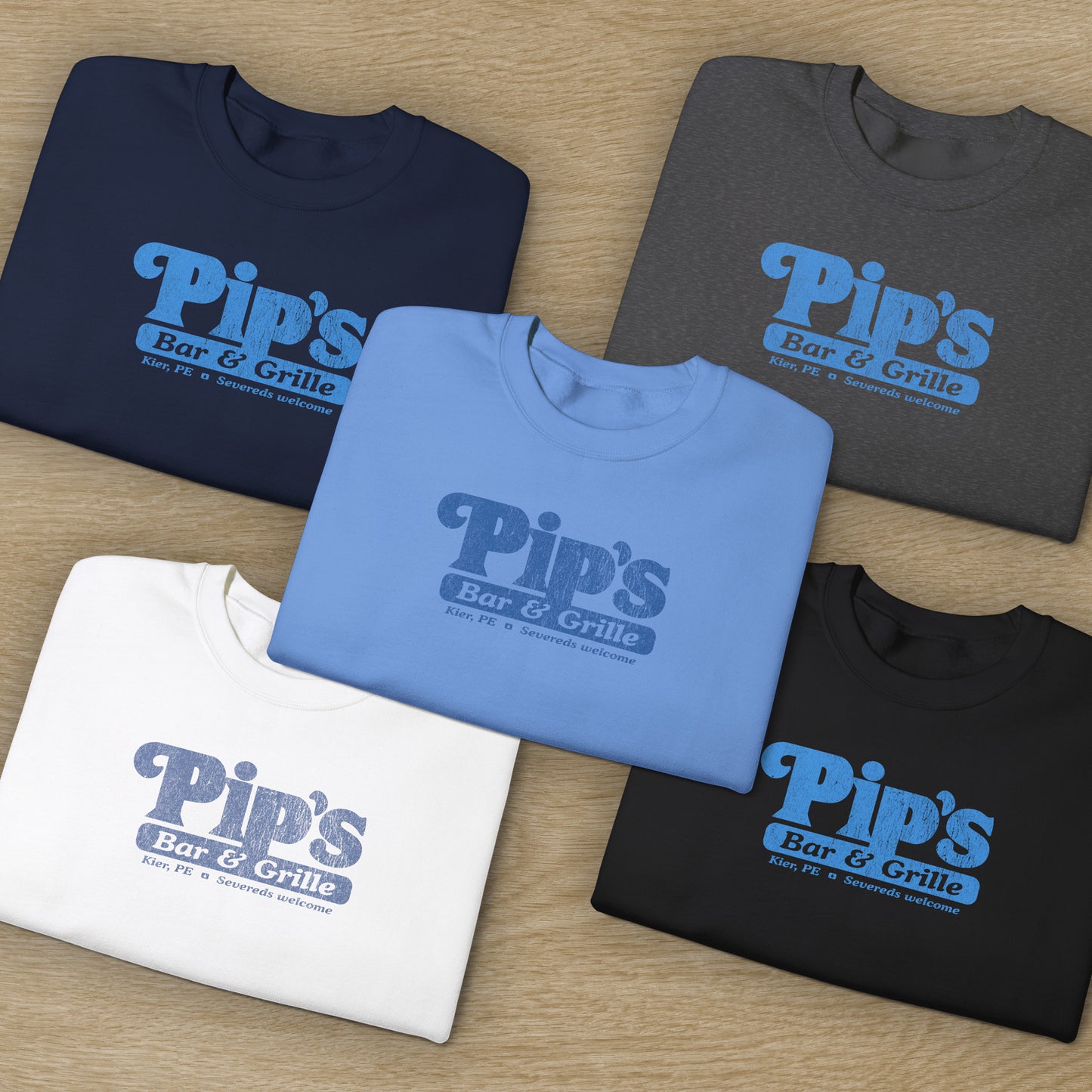 Group of 5 folded Soft Gildan 18000 sweatshirts featuring the Pips Bar and Grill logo Severeds Welcome from the TV show Severance in a vintage distressed ink-stamped worn-in style.