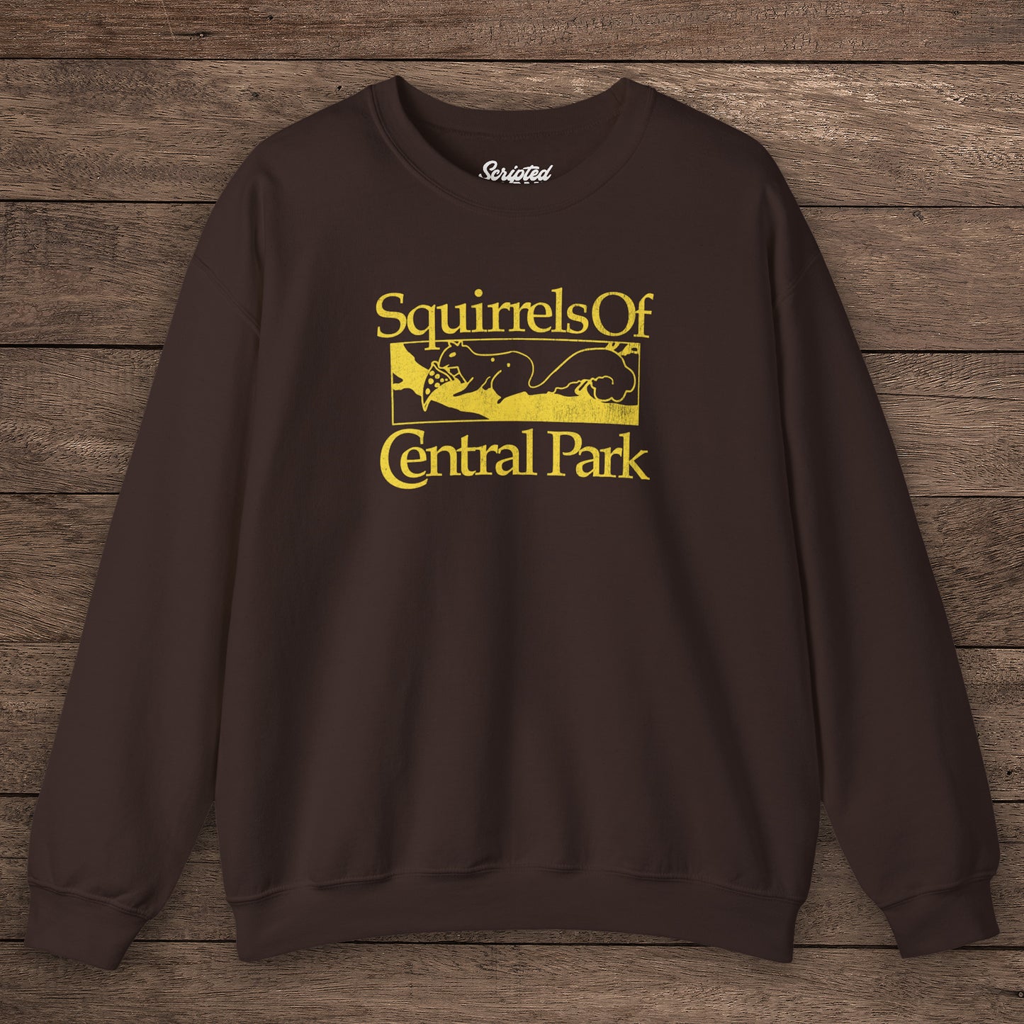 Chocolate brown Squirrels Of Central Park vintage distressed crewneck sweatshirt inspired by Bad Sisters, shown on wooden background.