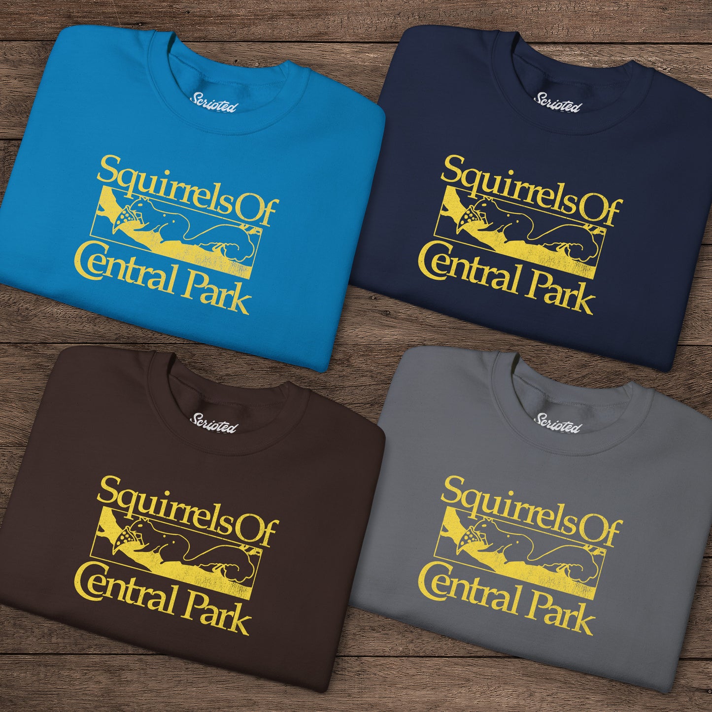 Four folded Squirrels Of Central Park vintage distressed crewneck sweatshirts inspired by Bad Sisters, shown on wooden background.