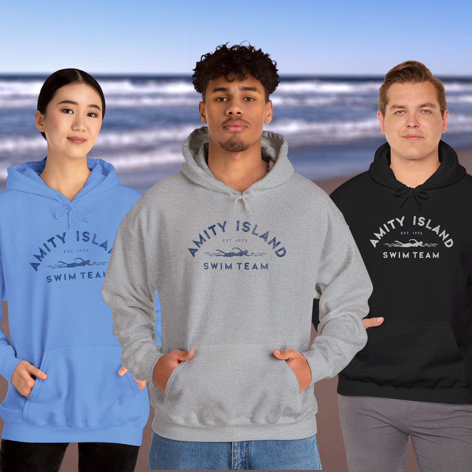 3 models wearing Soft Unisex Hoodie Heavy Blend Hooded Sweatshirts featuring an Amity Island Swim Team logo graphic, designed by ScriptedBrand, and  inspired by the movie Jaws in a vintage distressed style.