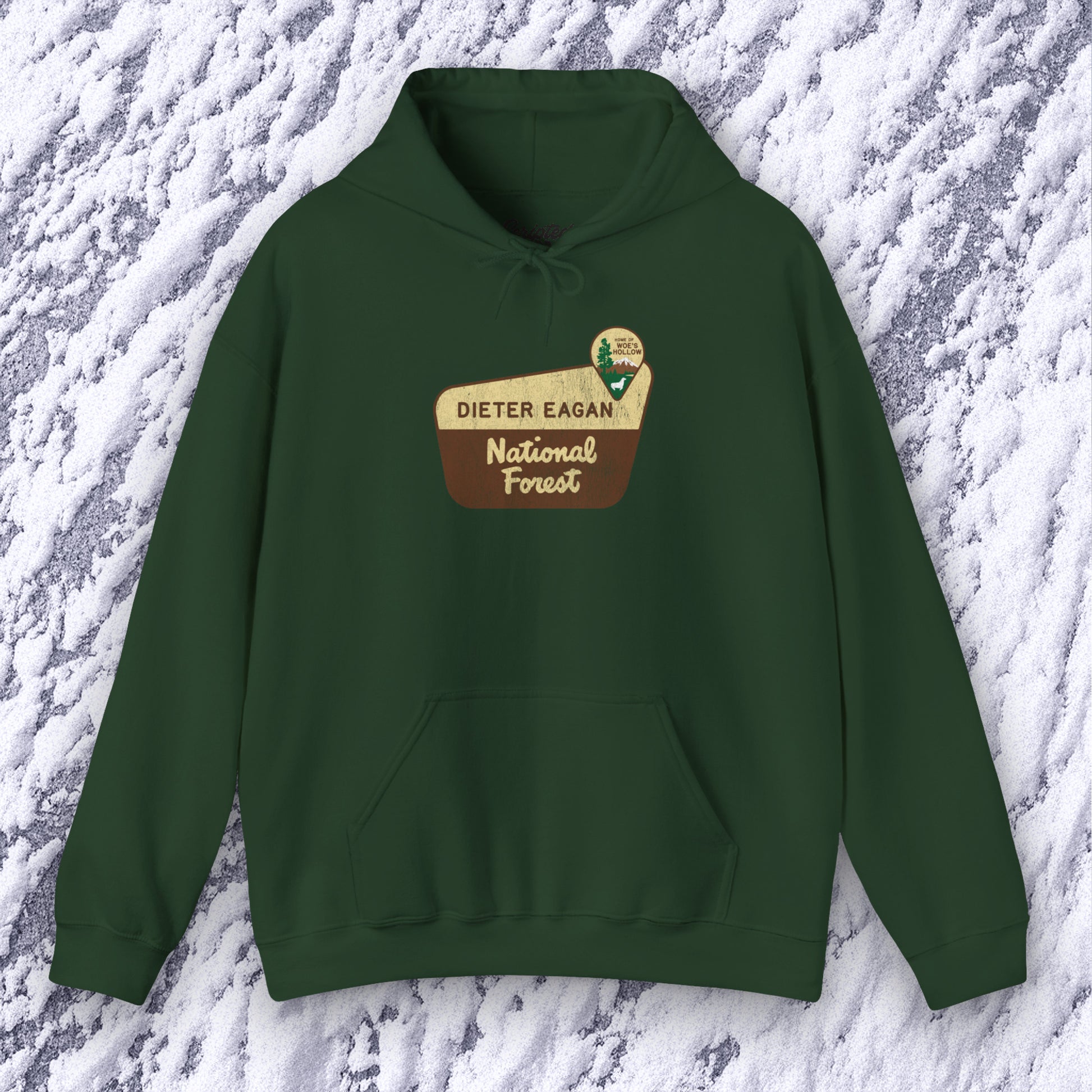 Mockup of a Forest green colored Soft Unisex Hoodie Heavy Blend Hooded Sweatshirt featuring the logo graphic of the Dieter Eagan National Forest inspired by the TV show Severance in a vintage distressed ink-stamped worn-in style.