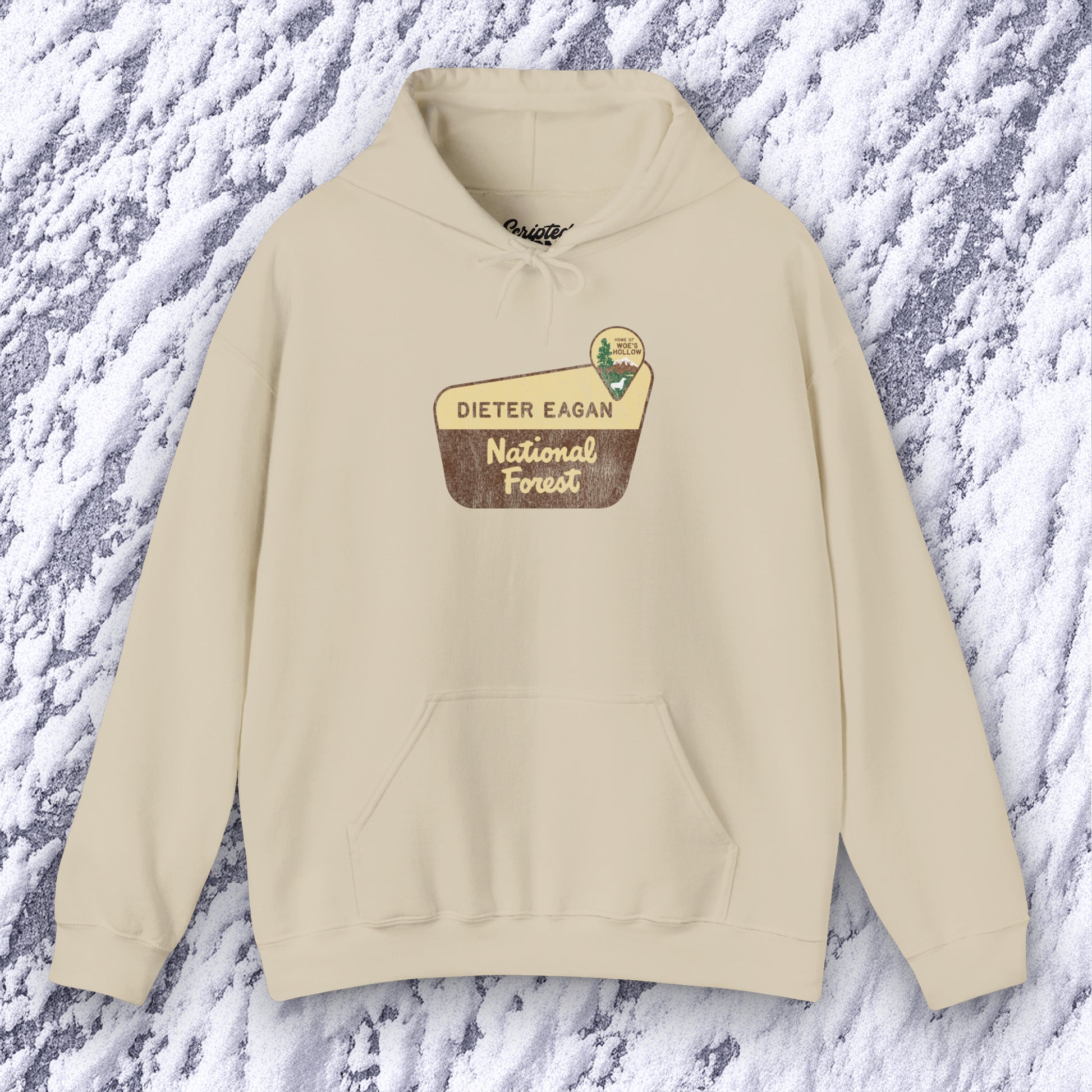 Mockup of a sand colored Soft Unisex Hoodie Heavy Blend Hooded Sweatshirt featuring the logo graphic of the Dieter Eagan National Forest inspired by the TV show Severance in a vintage distressed ink-stamped worn-in style.