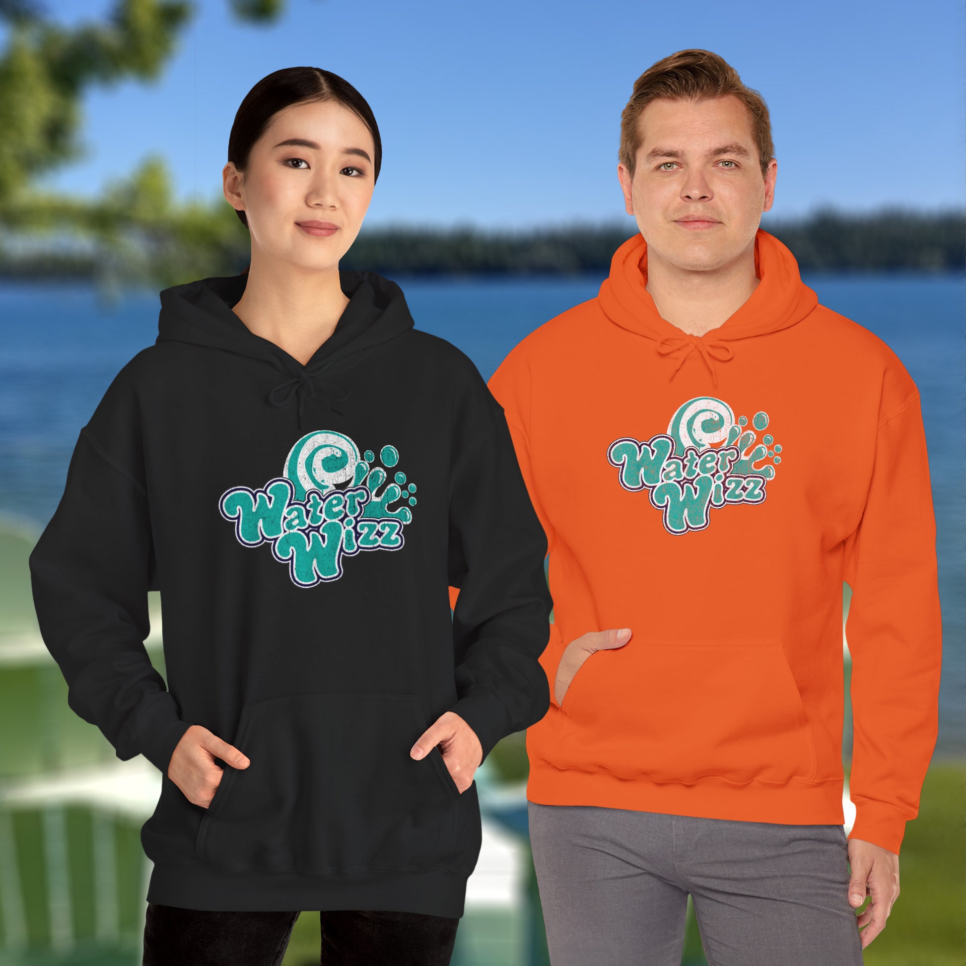Two people wearing Gildan 18500 pullover hoodies with vintage distressed Water Wizz logo from Grown Ups on the chest, shown near a lake.