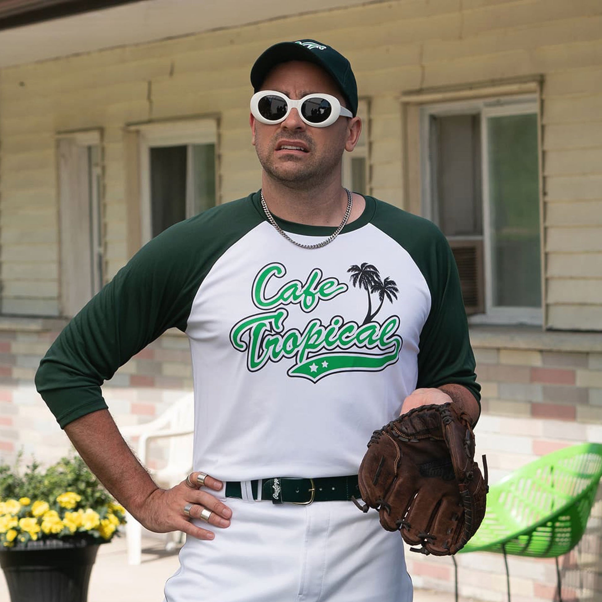 Character David Rose wearing a white and Green colored soft raglan 3/4 sleeve baseball shirt featuring the fictional Cafe Tropical logo in the TV Show Schitts Creek.