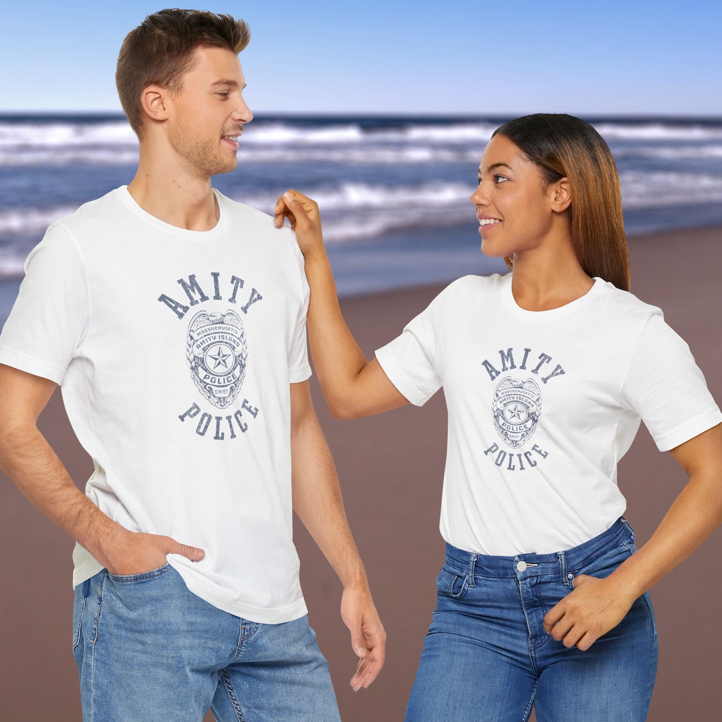2 models wearing white colored Soft unisex Bella+Canvas 3001 short-sleeve t-shirts featuring an Amity Island Police logo graphic, designed by ScriptedBrand, and  inspired by the movie Jaws in a vintage distressed style.