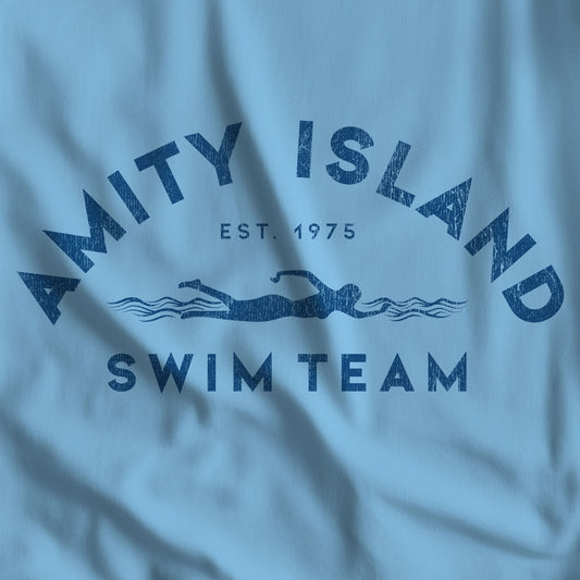 Closeup of ocean blue t-shirt featuring an Amity Island Swim Team logo graphic inspired by the movie Jaws in a vintage distressed style.