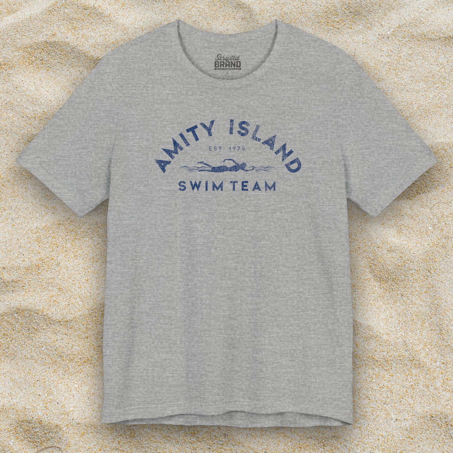 Front view of an Athletic Heather Grey colored Soft unisex Bella+Canvas 3001 short-sleeve t-shirt featuring an Amity Island Swim Team logo graphic, designed by ScriptedBrand, and  inspired by the movie Jaws in a vintage distressed style.