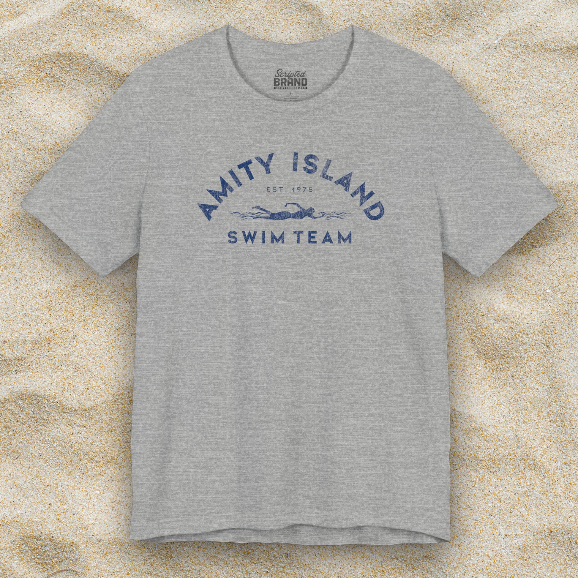 Front view of an Athletic Heather Grey colored Soft unisex Bella+Canvas 3001 short-sleeve t-shirt featuring an Amity Island Swim Team logo graphic, designed by ScriptedBrand, and  inspired by the movie Jaws in a vintage distressed style.