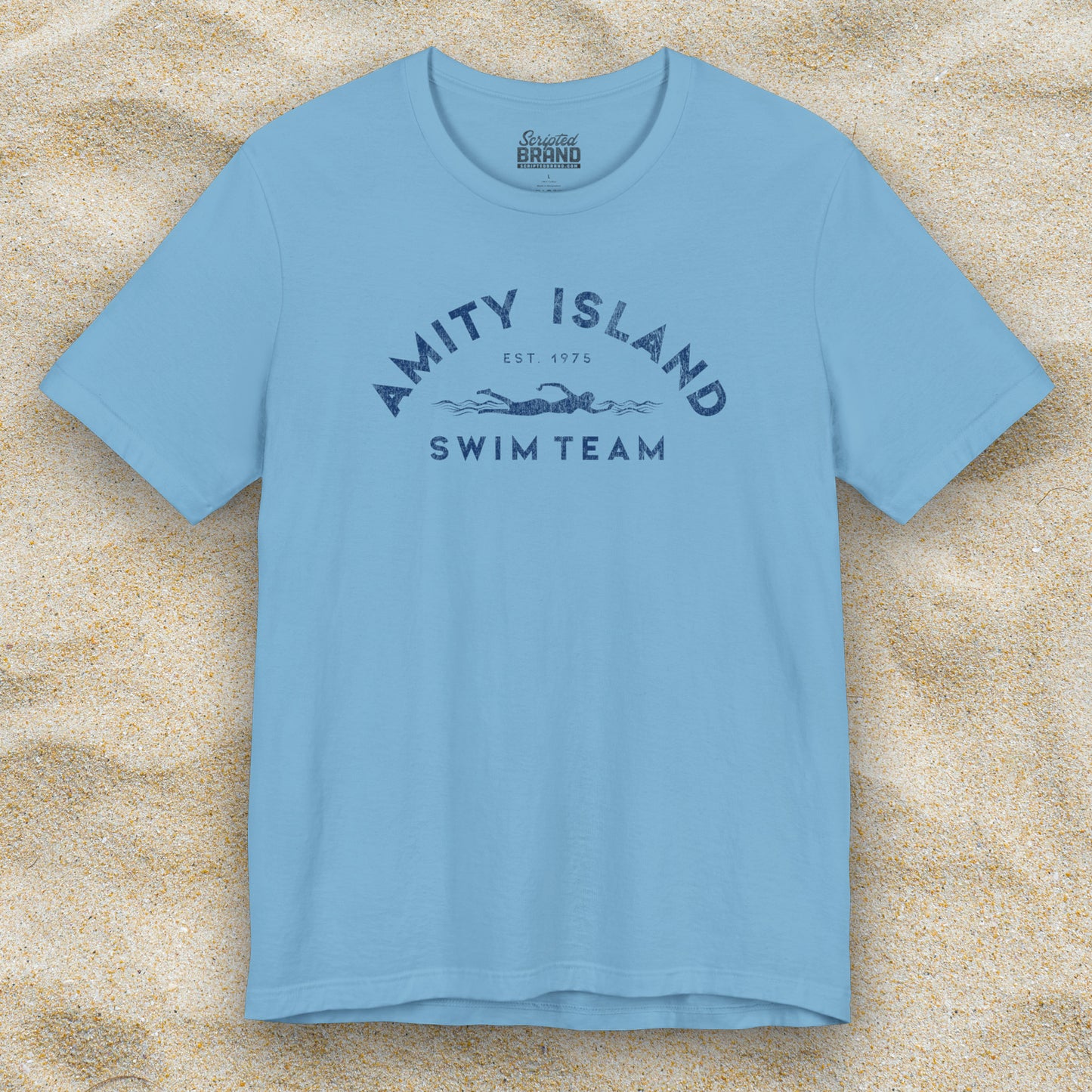 Front view of an Ocean Blue colored Soft unisex Bella+Canvas 3001 short-sleeve t-shirt featuring an Amity Island Swim Team logo graphic, designed by ScriptedBrand, and  inspired by the movie Jaws in a vintage distressed style.