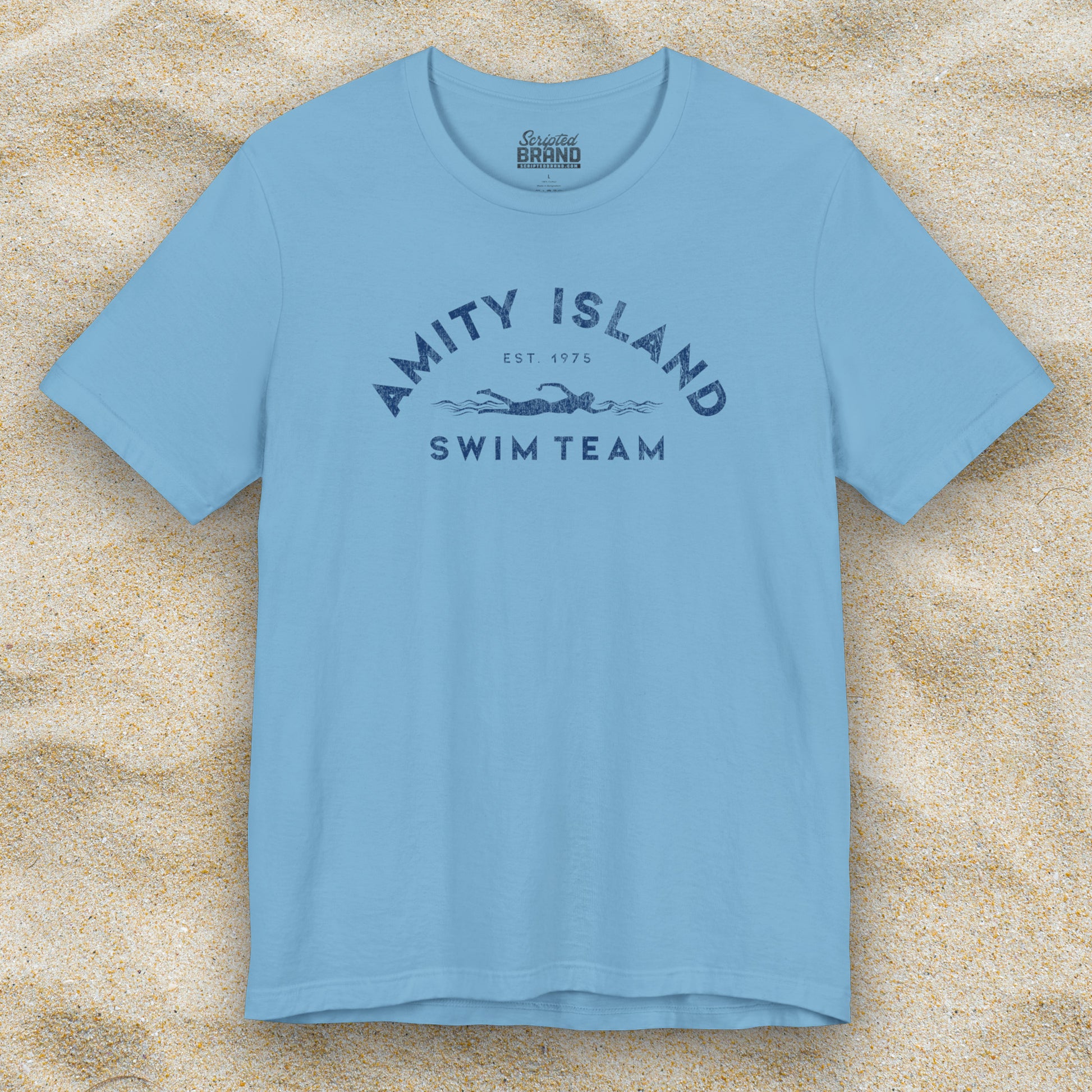 Front view of an Ocean Blue colored Soft unisex Bella+Canvas 3001 short-sleeve t-shirt featuring an Amity Island Swim Team logo graphic, designed by ScriptedBrand, and  inspired by the movie Jaws in a vintage distressed style.