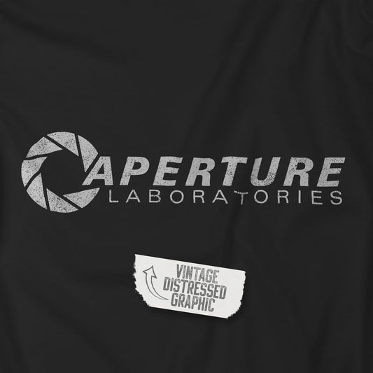 Closeup view of a Black colored soft Bella+Canvas t-shirt with the Aperture Laboratories logo from the video game Portal and Portal 2 in a vintage ink-stamped distressed style, sold by ScriptedBrand. 