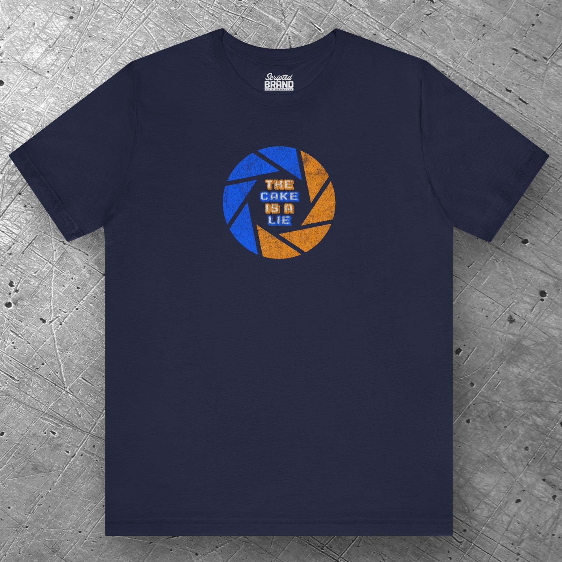 Front view of a navy blue colored soft Bella+Canvas 3001 short-sleeve t-shirt featuring the phrase The Cake Is a Lie, along with the Aperture Laboratories shutter logo from the video game Portal and Portal 2 in a vintage distressed style, sold by ScriptedBrand.