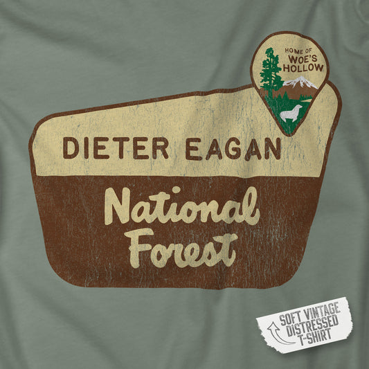 Closeup view of a logo graphic of the Dieter Eagan National Forest sign on a t-shirt, inspired by the TV show Severance, vintage distressed style.