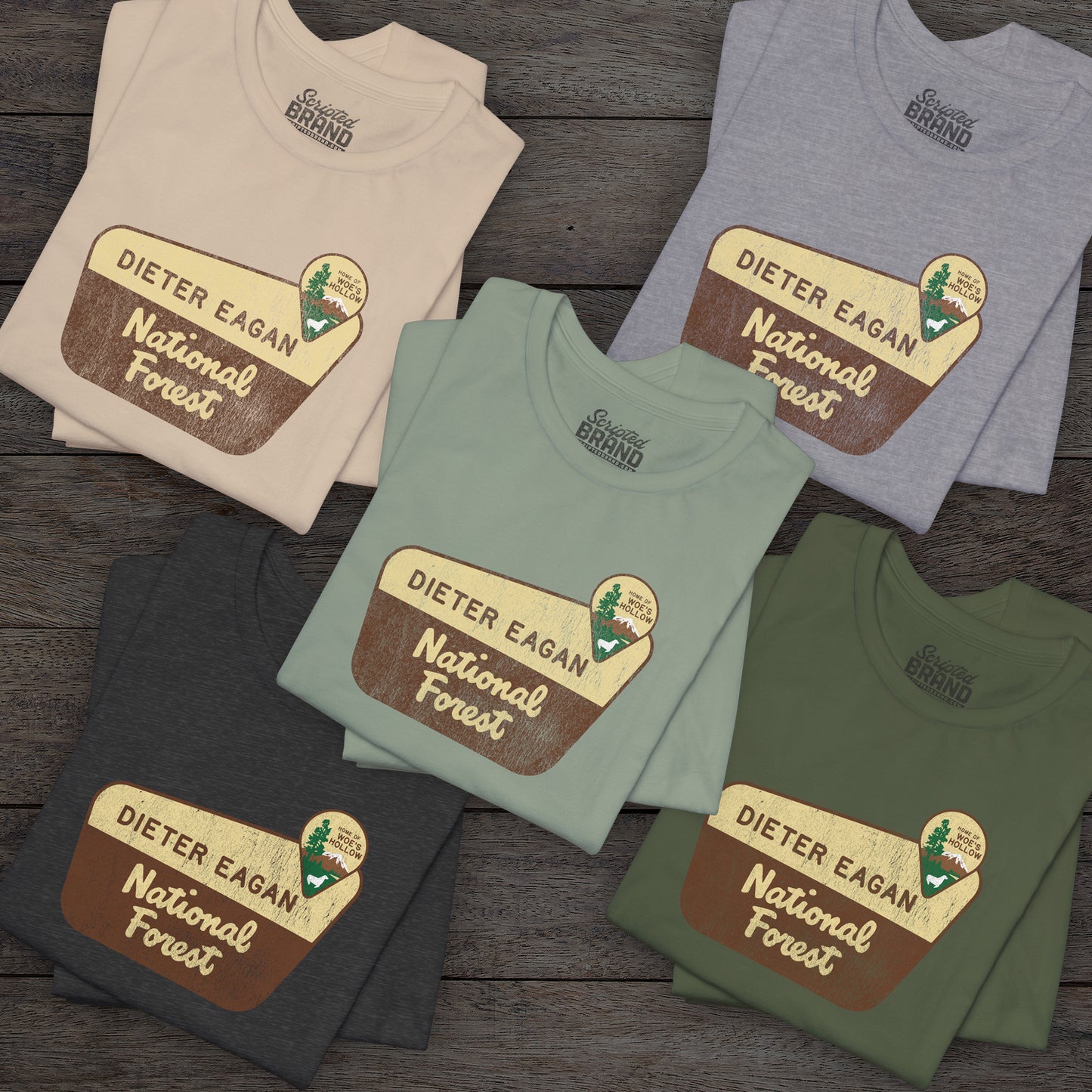 Group of 5 folded soft Bella+Canvas short-sleeve t-shirt with the logo graphic of the Dieter Eagan National Forest inspired by the TV show Severance in a vintage distressed ink-stamped worn-in style.