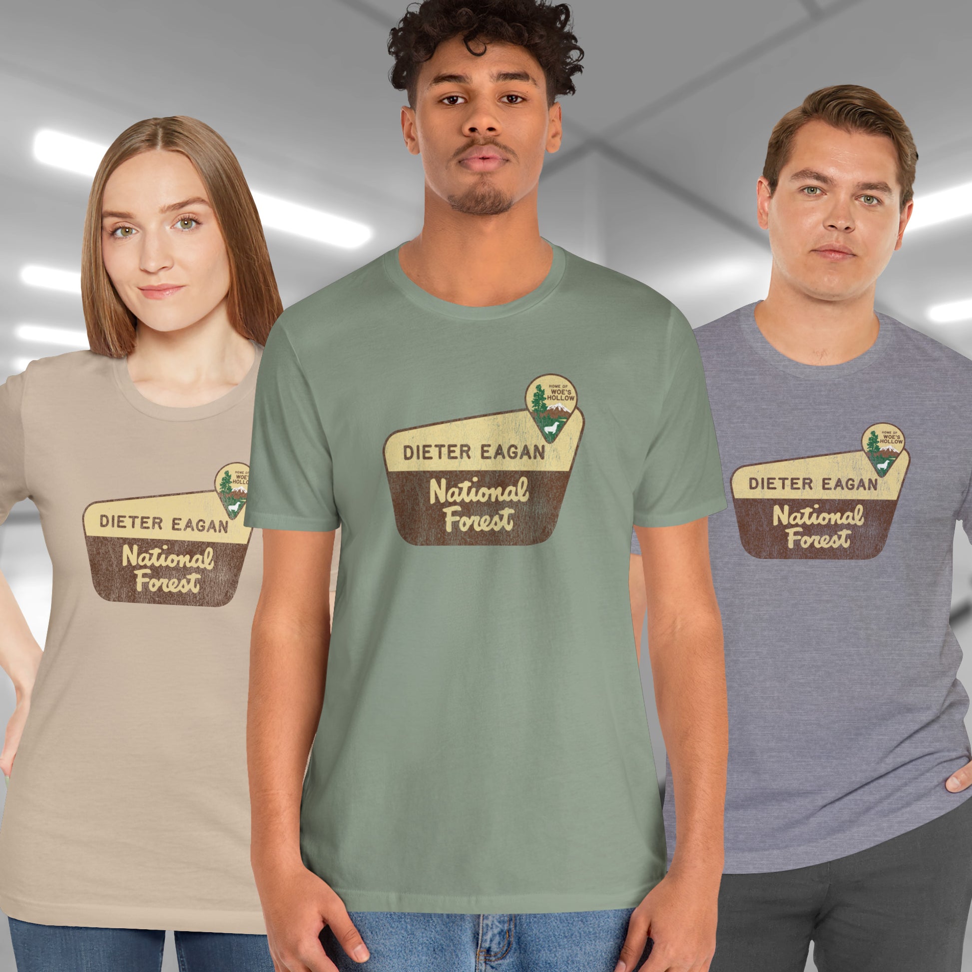 3 models wearing soft Bella+Canvas short-sleeve t-shirts with the logo graphic of the Dieter Eagan National Forest inspired by the TV show Severance in a vintage distressed ink-stamped worn-in style.