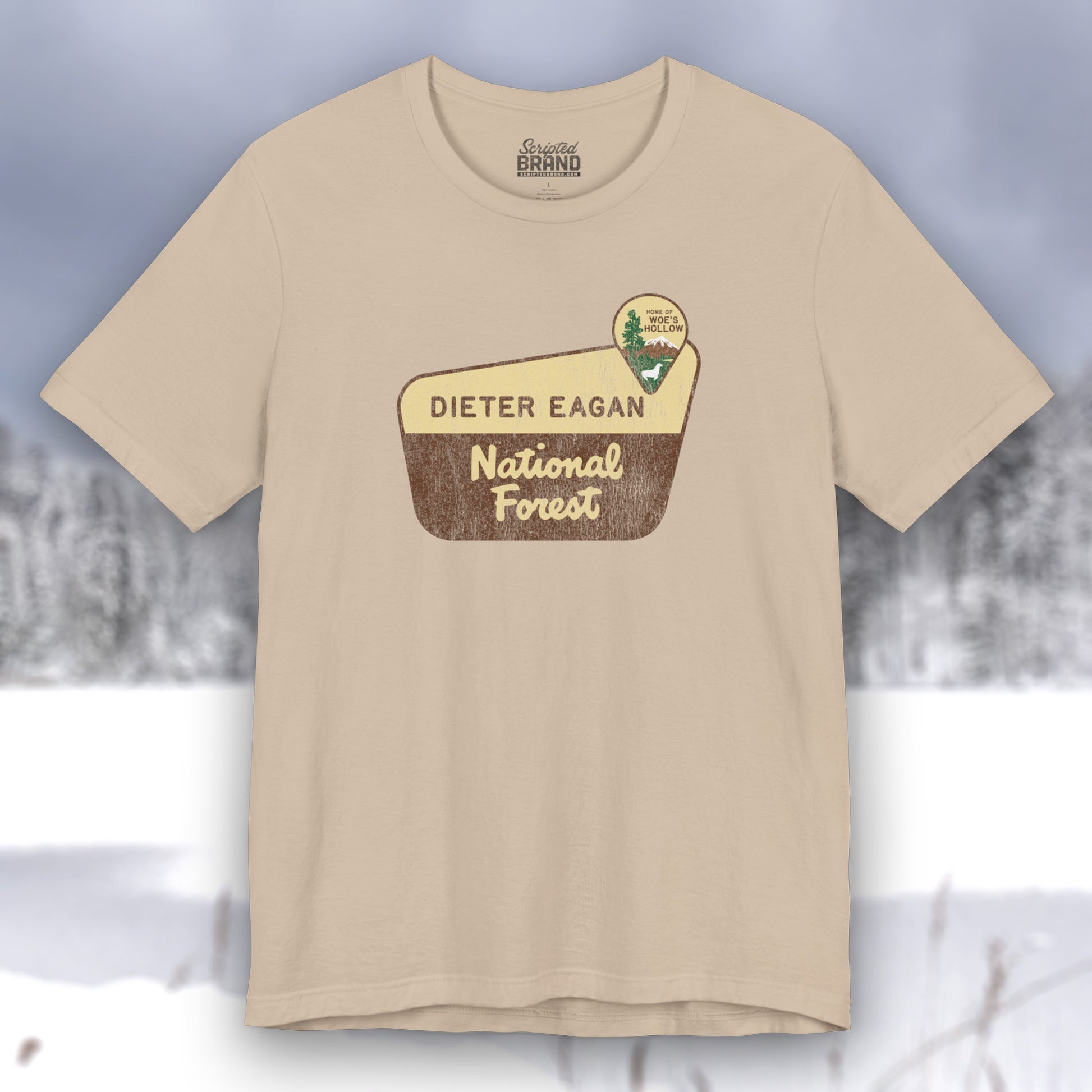 Tan colored soft Bella+Canvas short-sleeve t-shirt with the logo graphic of the Dieter Eagan National Forest inspired by the TV show Severance in a vintage distressed ink-stamped worn-in style.