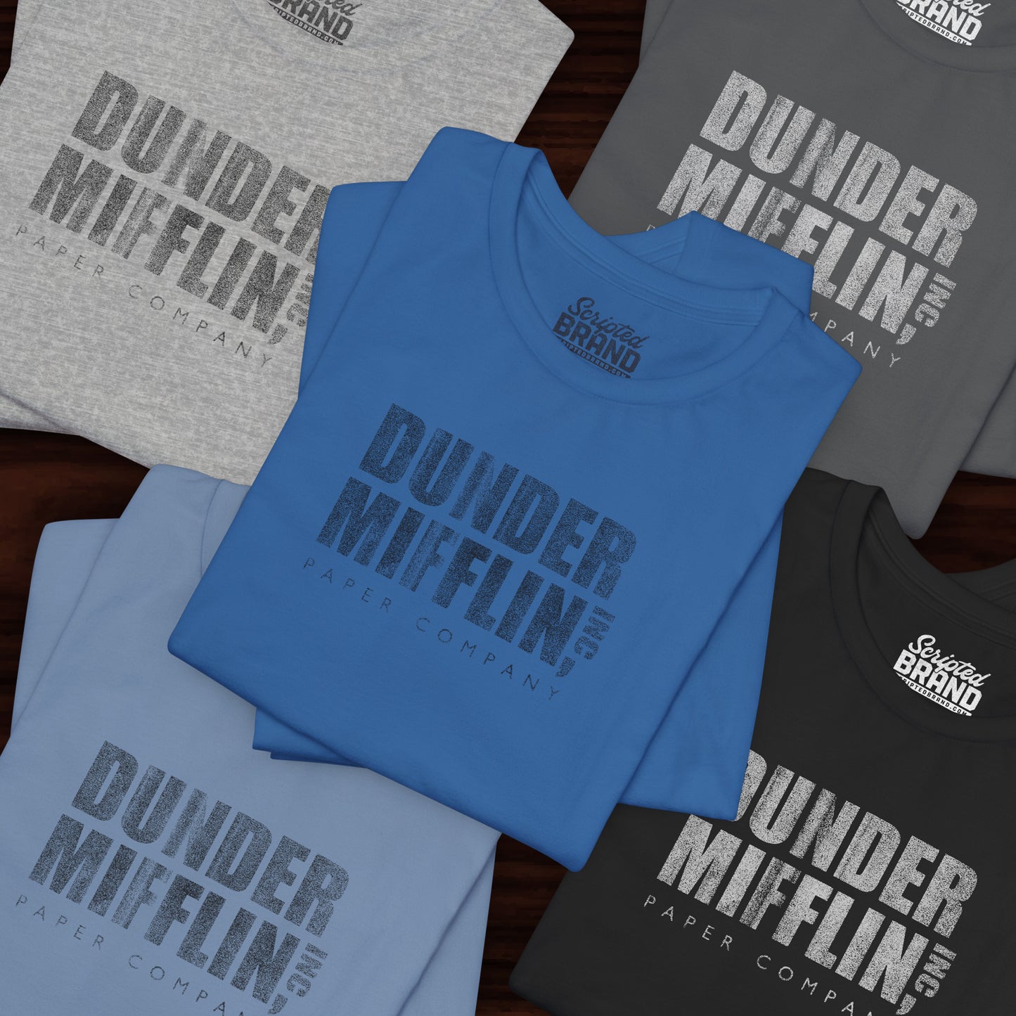 Five folded t-shirts featuring the Dunder Mifflin logo from the TV show The Office in a vintage distressed style.
