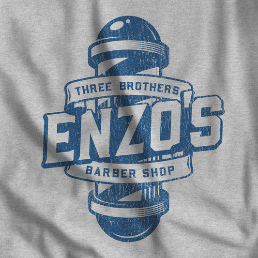 Closeup of athletic heather gray t-shirt with the Enzo's Barber Shop logo graphic inspired by the TV show Seinfeld in a vintage distressed style.