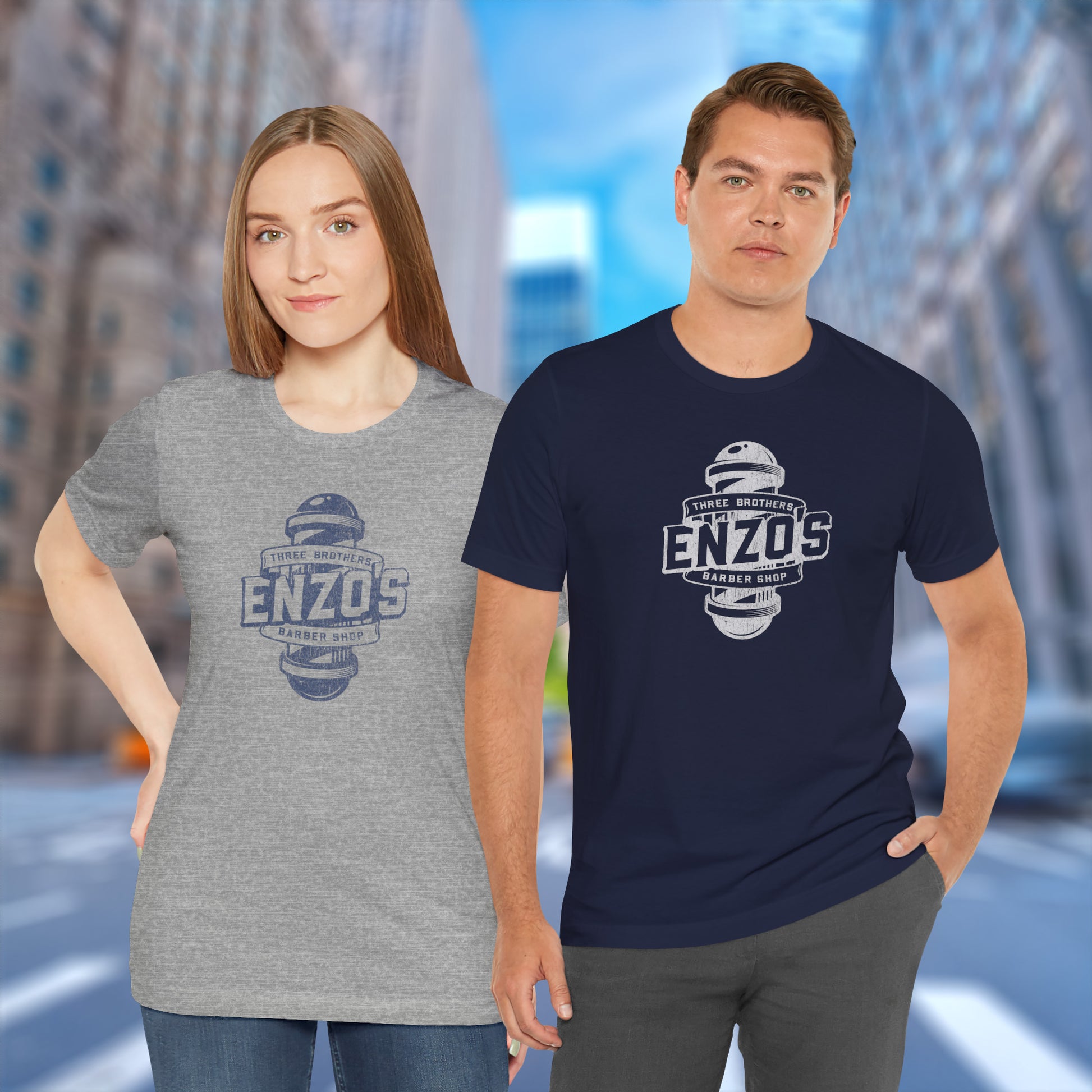 Two people wearing t-shirts with the Enzo's Barber Shop logo graphic inspired by the TV show Seinfeld in a vintage distressed style.