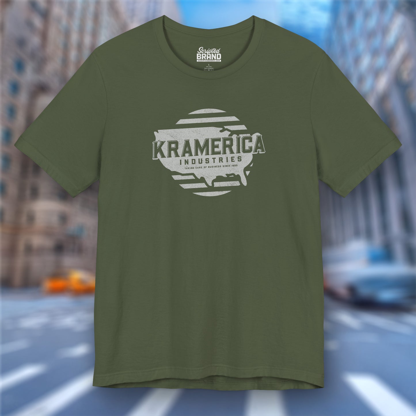 Military green t-shirt featuring a Kramerica logo graphic inspired by the TV show Seinfeld in a vintage distressed style.