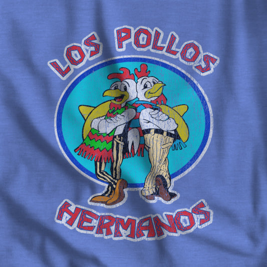 Closeup of blue t-shirt featuring a distressed graphic of two cartoon chickens with the text "Los Pollos Hermanos" in a circular design
