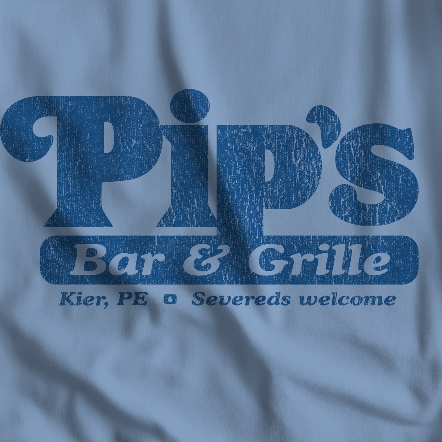 Closeup of Steel blue Bella+Canvas t-shirt with the Pips Bar and Grill logo from the TV show Severance in a vintage distressed style.
