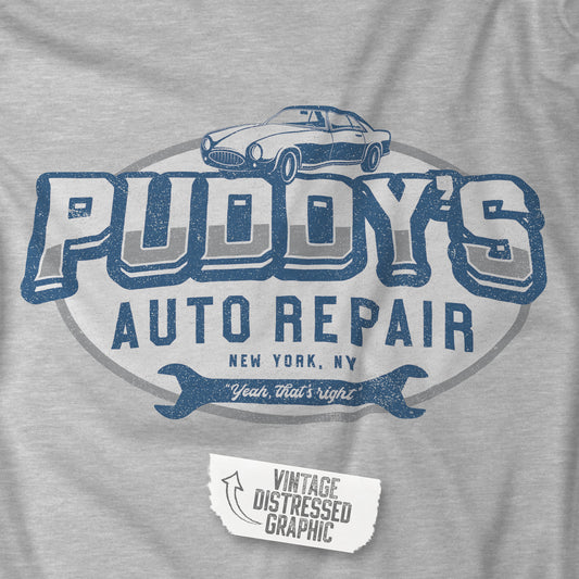 Closeup of an athletic heather grey soft short-sleeve t-shirt featuring a Puddy's Auto Repair logo graphic inspired by the TV show Seinfeld, designed by ScriptedBrand in a vintage distressed style.