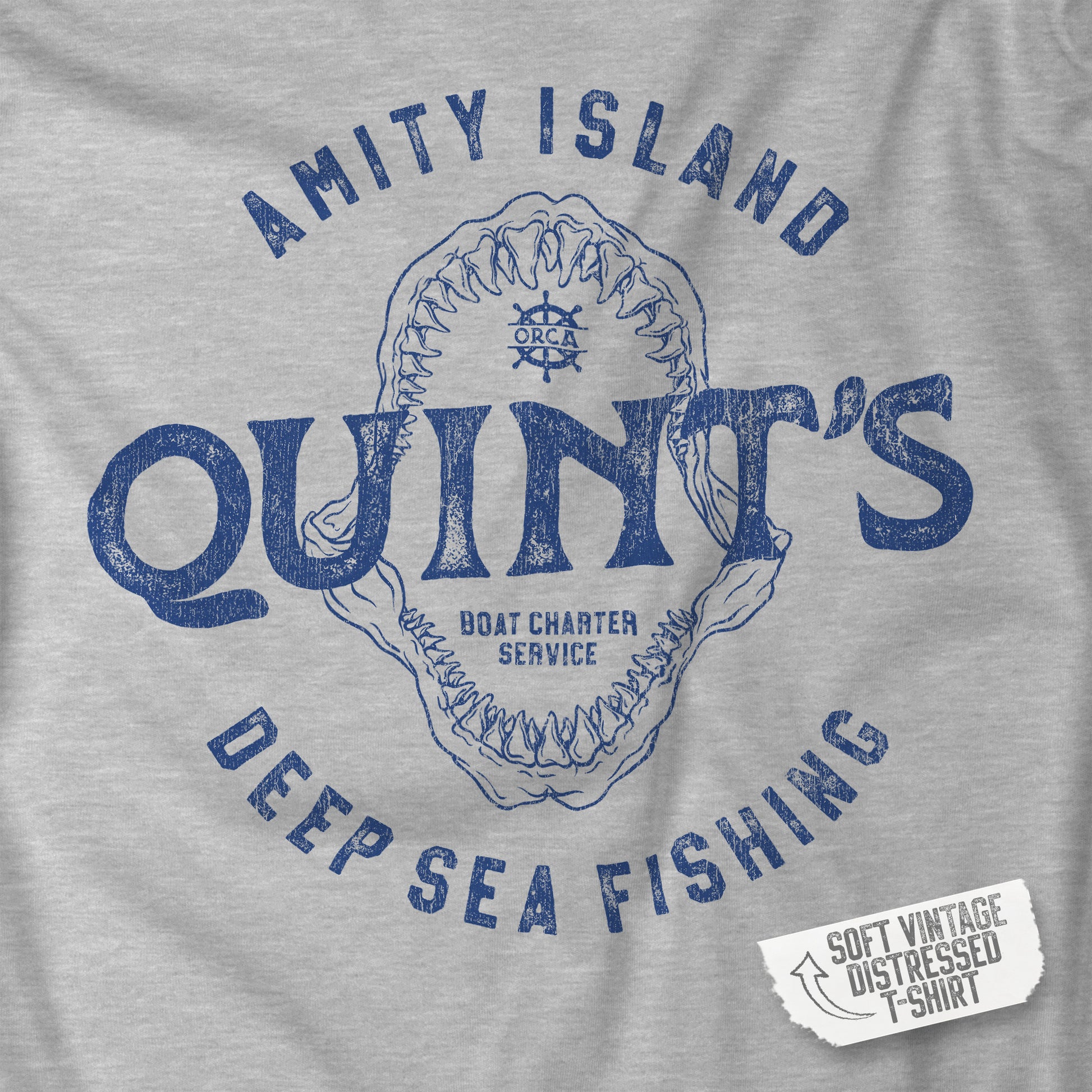 Closeup of a Athletic Heather Gray Soft short-sleeve t-shirt featuring the Quint's Deep Sea Fishing Boat Charters logo graphic inspired by the movie Jaws in a vintage distressed ink-stamped worn-in style.
