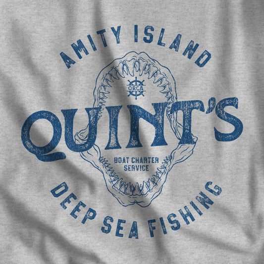 Closeup of t-shirt featuring the Quint's Deep Sea Fishing Boat Charters logo graphic inspired by the movie Jaws in a vintage distressed style.