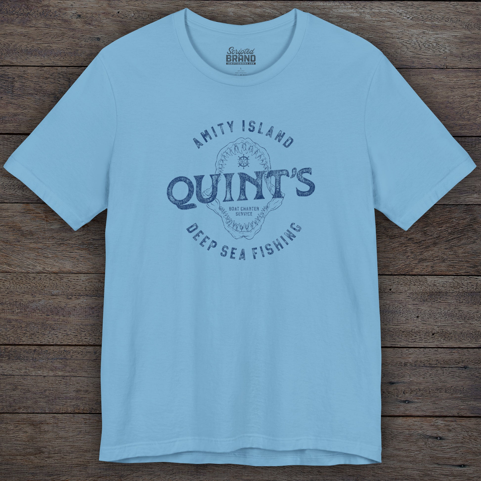 Ocean blue colored Soft short-sleeve t-shirt featuring the Quint's Deep Sea Fishing Boat Charters logo graphic inspired by the movie Jaws in a vintage distressed ink-stamped worn-in style.