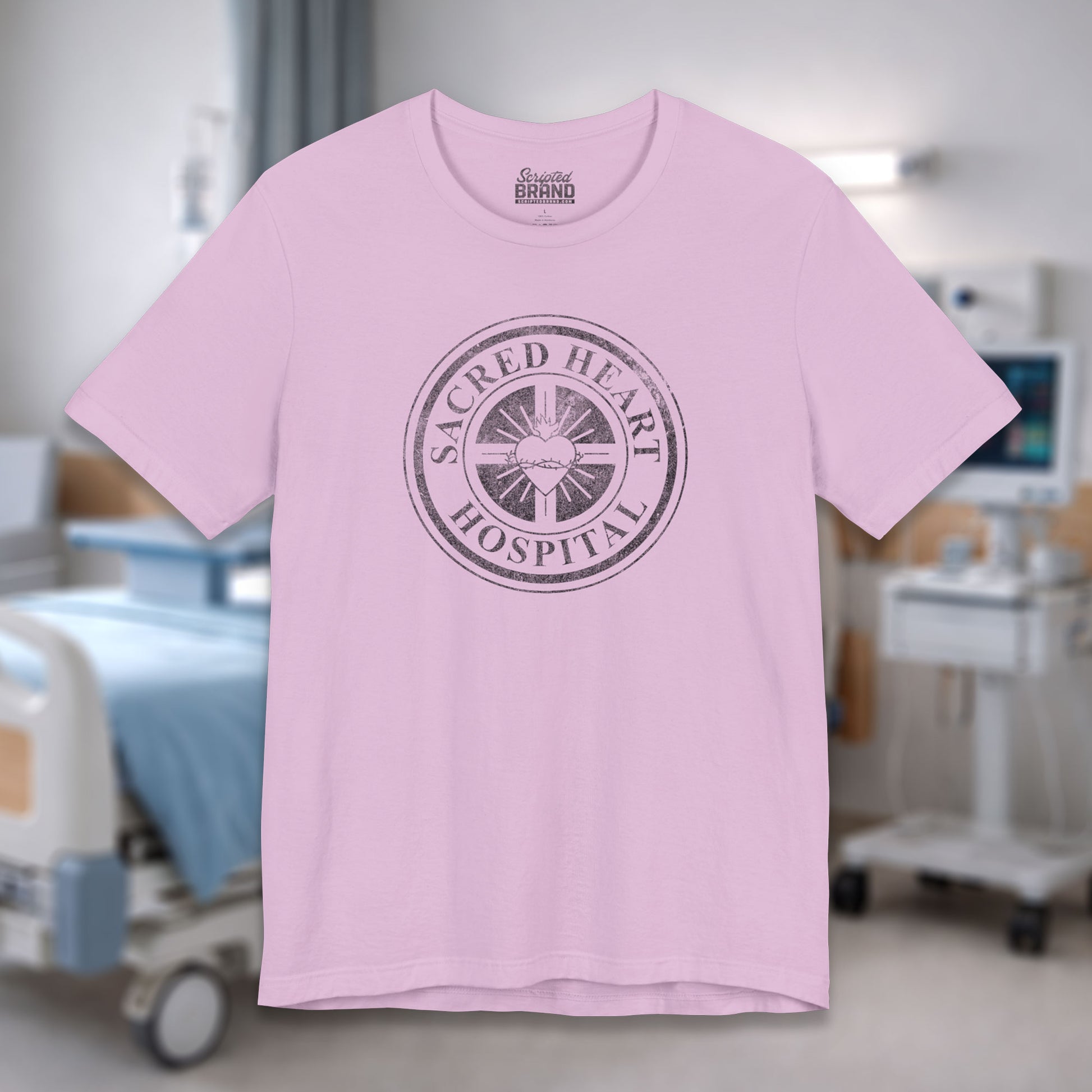 Lilac Bella Canvas 3001 tee with vintage distressed Sacred Heart Hospital logo from Scrubs printed on chest, shown in a hospital.