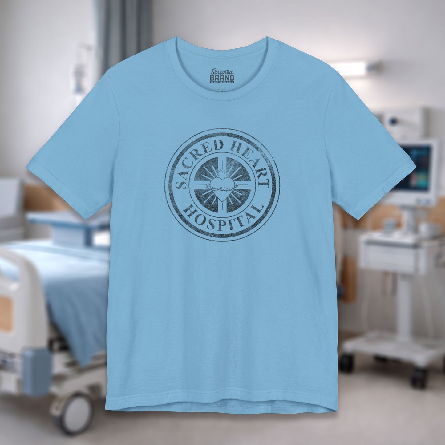 Ocean blue Bella Canvas 3001 tee with vintage distressed Sacred Heart Hospital logo from Scrubs printed on chest, shown in a hospital.