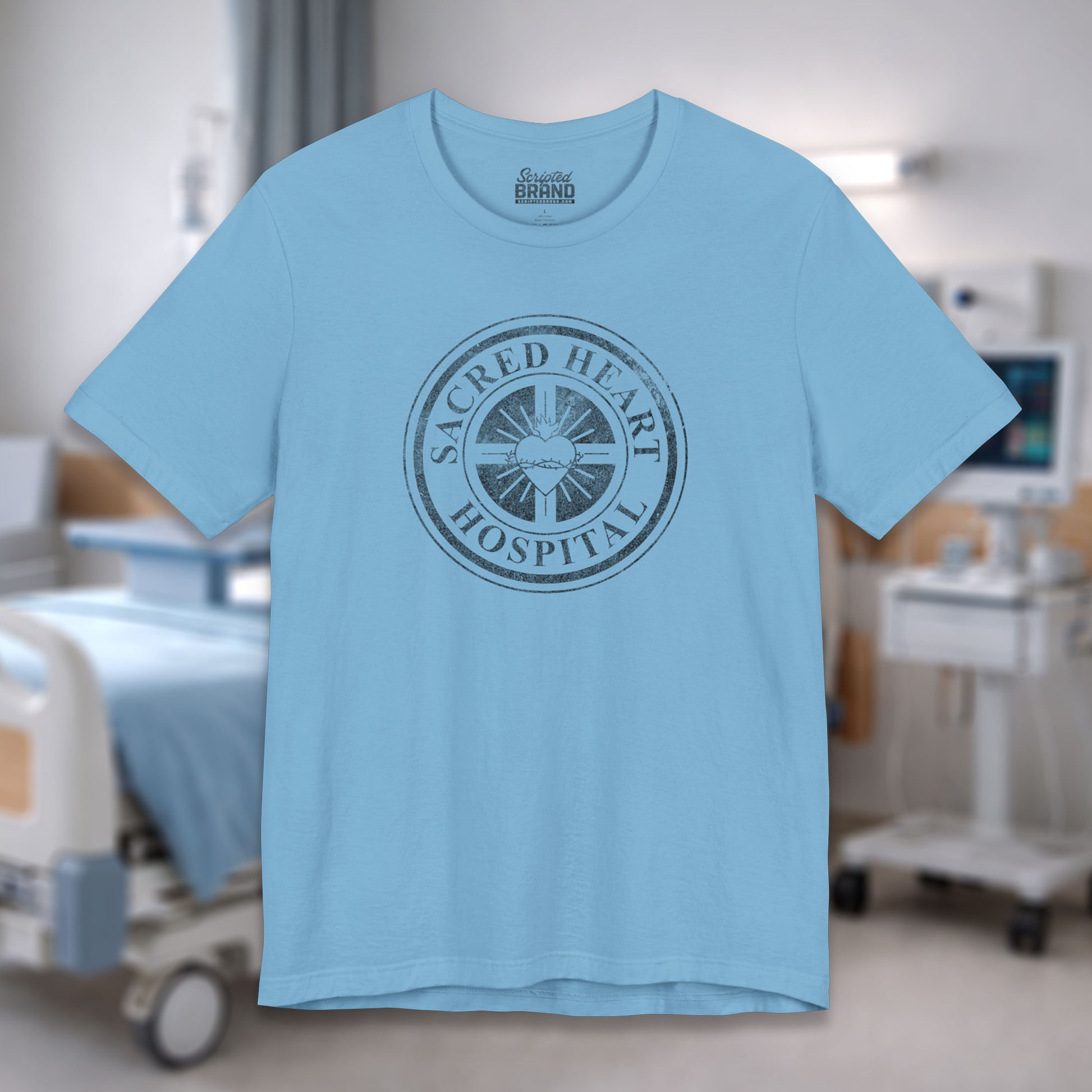 Ocean blue Bella Canvas 3001 tee with vintage distressed Sacred Heart Hospital logo from Scrubs printed on chest, shown in a hospital.