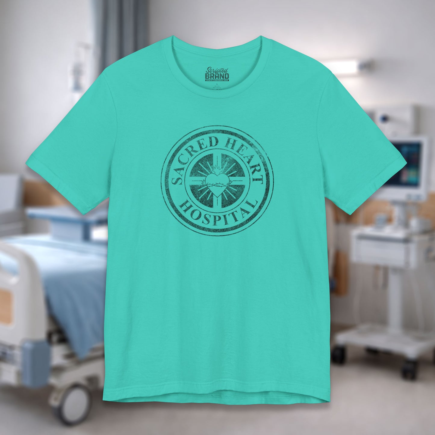 Teal Bella Canvas 3001 tee with vintage distressed Sacred Heart Hospital logo from Scrubs printed on chest, shown in a hospital.