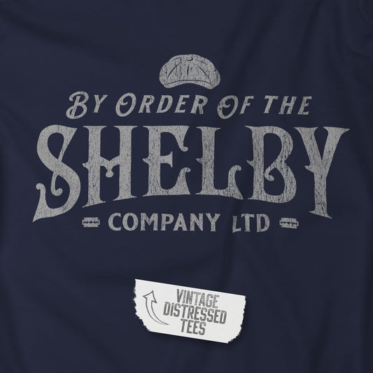 Closeup of a Navy blue colored soft short-sleeve Bella+Canvas 3001 t-shirt featuring a unique Shelby Company Limited logo graphic from the show Peaky Blinders and movie The Immortal Man, in a vintage distressed style, includes a flat cap and razor blades, designed and sold by ScriptedBrand.