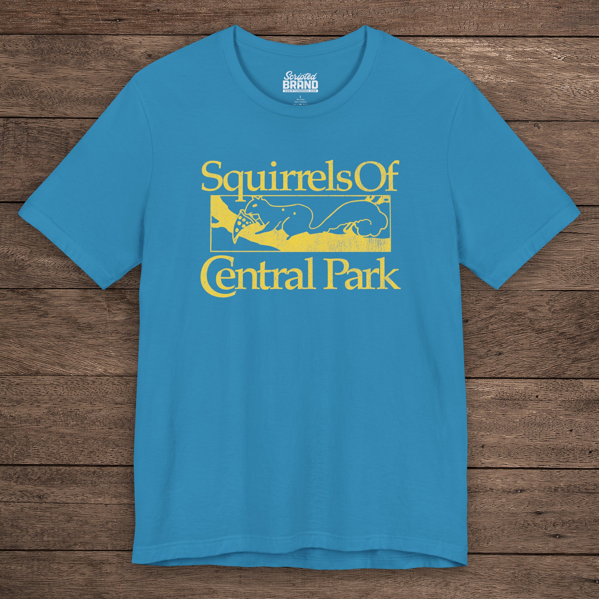 Aqua blue unisex t-shirt with distressed yellow “Squirrels of Central Park” graphic, worn by Eva Garvey in the show Bad Sisters.