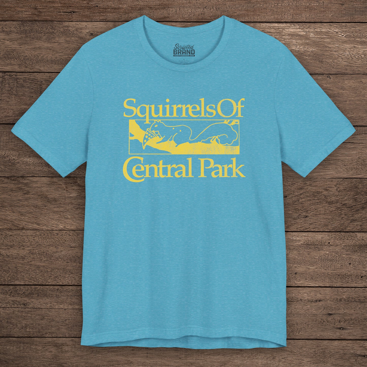 Heather Aqua blue unisex t-shirt with distressed yellow “Squirrels of Central Park” graphic, worn by Eva Garvey in the show Bad Sisters.