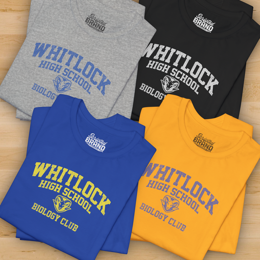 Four folded t-shirts with 'Whitlock High School Biology Club' text on a wooden surface.