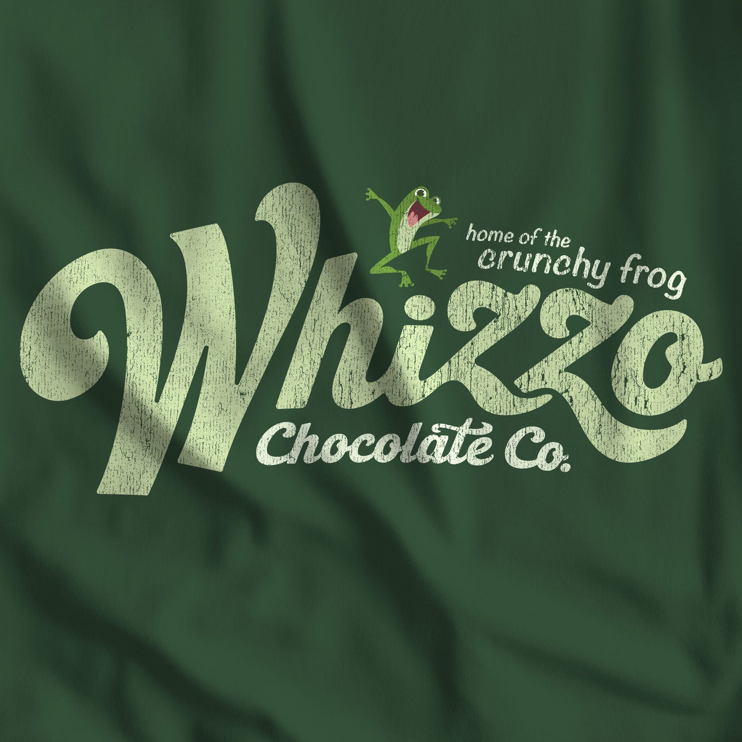 Closeup of Forest green t-shirt with Whizzo Chocolate Co logo inspired by Monty Python, featuring “home of the crunchy frog” distressed graphic