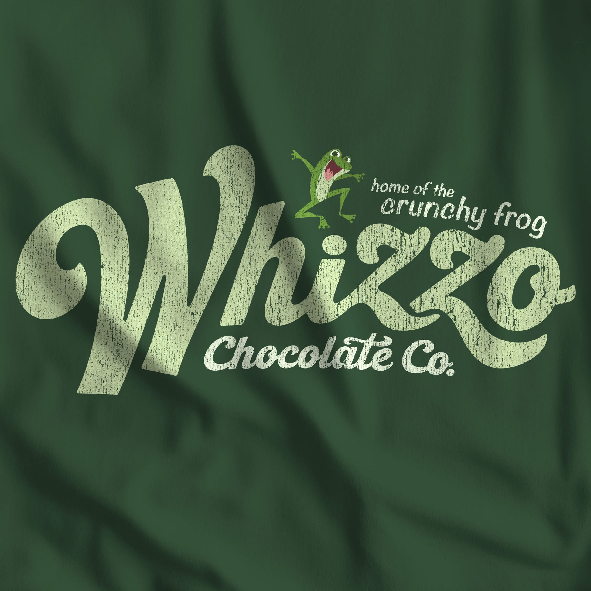Closeup of Forest green t-shirt with Whizzo Chocolate Co logo inspired by Monty Python, featuring “home of the crunchy frog” distressed graphic