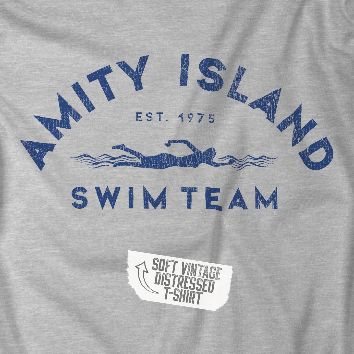 Closeup view of an athletic heather grey colored Soft unisex Youth Sizes Bella+Canvas 3001Y short-sleeve t-shirt featuring an Amity Island Swim Team logo graphic, designed by ScriptedBrand, and  inspired by the movie Jaws in a vintage distressed style.