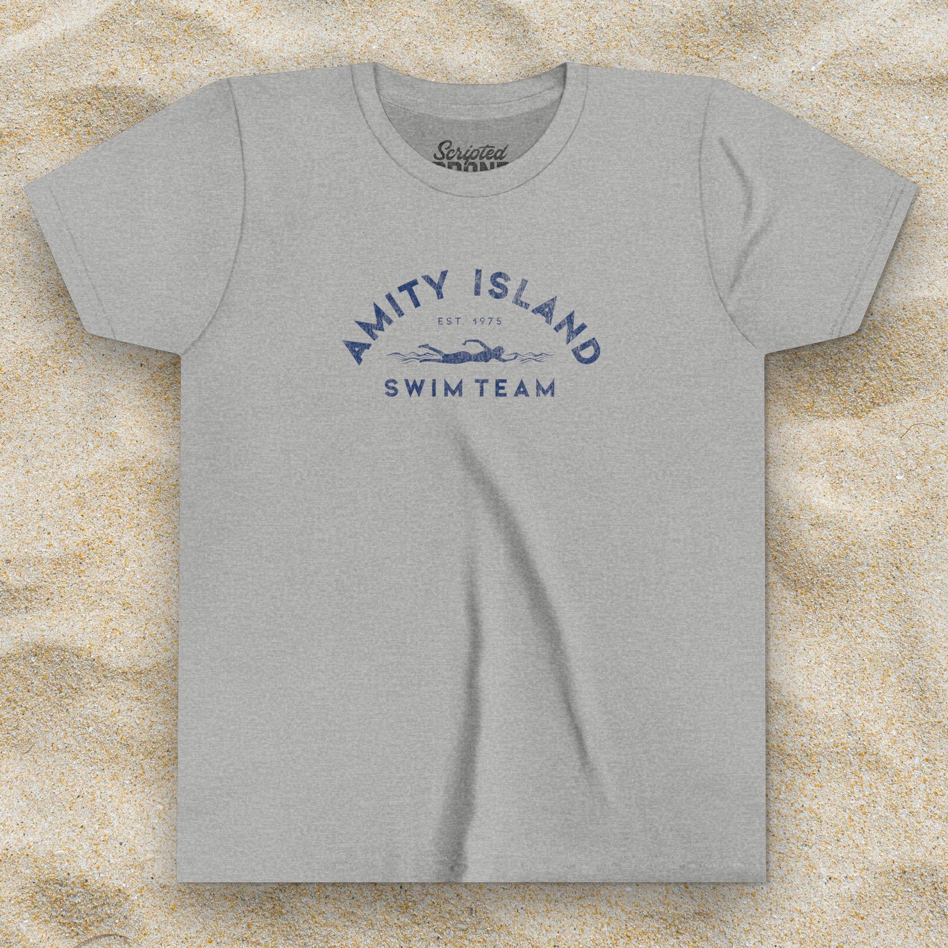 Front view of an Athletic Heather grey colored Soft unisex Youth Sizes Bella+Canvas 3001Y short-sleeve t-shirt featuring an Amity Island Swim Team logo graphic, designed by ScriptedBrand, and  inspired by the movie Jaws in a vintage distressed style.