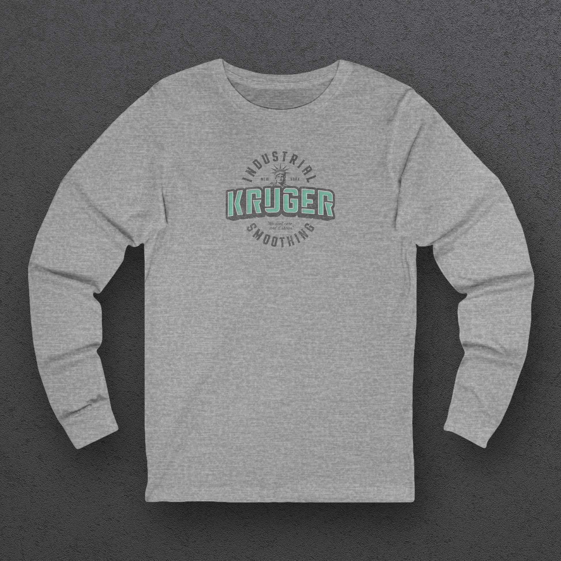 Front view of a grey athletic heather colored soft unisex Bella+Canvas 3501 long-sleeve t-shirt featuring a Kruger Industrial Smoothing logo graphic, designed by ScriptedBrand in a vintage distressed style, and  inspired by the TV show Seinfeld. Includes the Statue of Liberty and the the slogan "We don't care and it shows".
