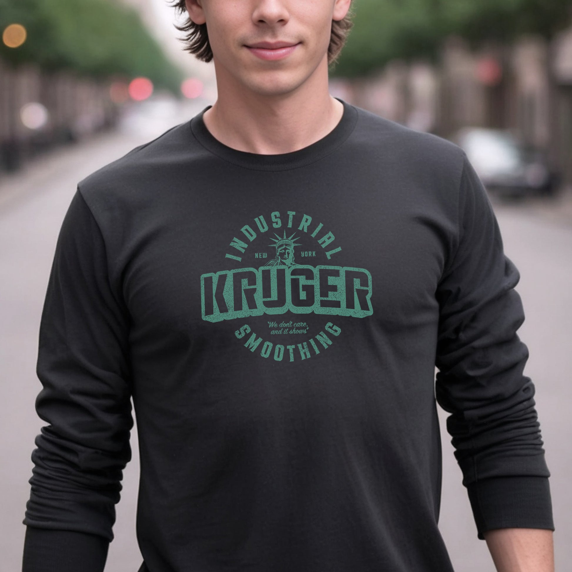 Male model wearing a black colored soft unisex Bella+Canvas 3501 long-sleeve t-shirt featuring a Kruger Industrial Smoothing logo graphic, designed by ScriptedBrand in a vintage distressed style, and  inspired by the TV show Seinfeld. Includes the Statue of Liberty and the the slogan "We don't care and it shows".