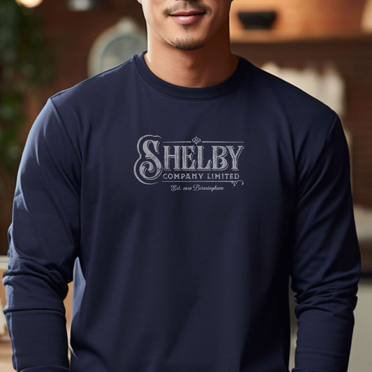 Male model wearing a navy blue soft unisex Bella-Canvas 3501 long-sleeve t-shirt featuring the Shelby Company Limited logo from the show Peaky Blinders in a vintage distressed style, sold by ScriptedBrand.